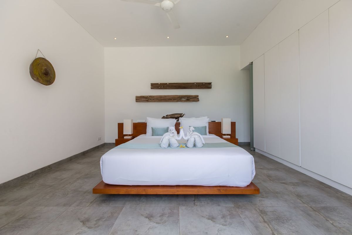 Modern luxury bathroom with wooden double vanity, white marble countertop, orchids, and folded towels. - Bali Villas
