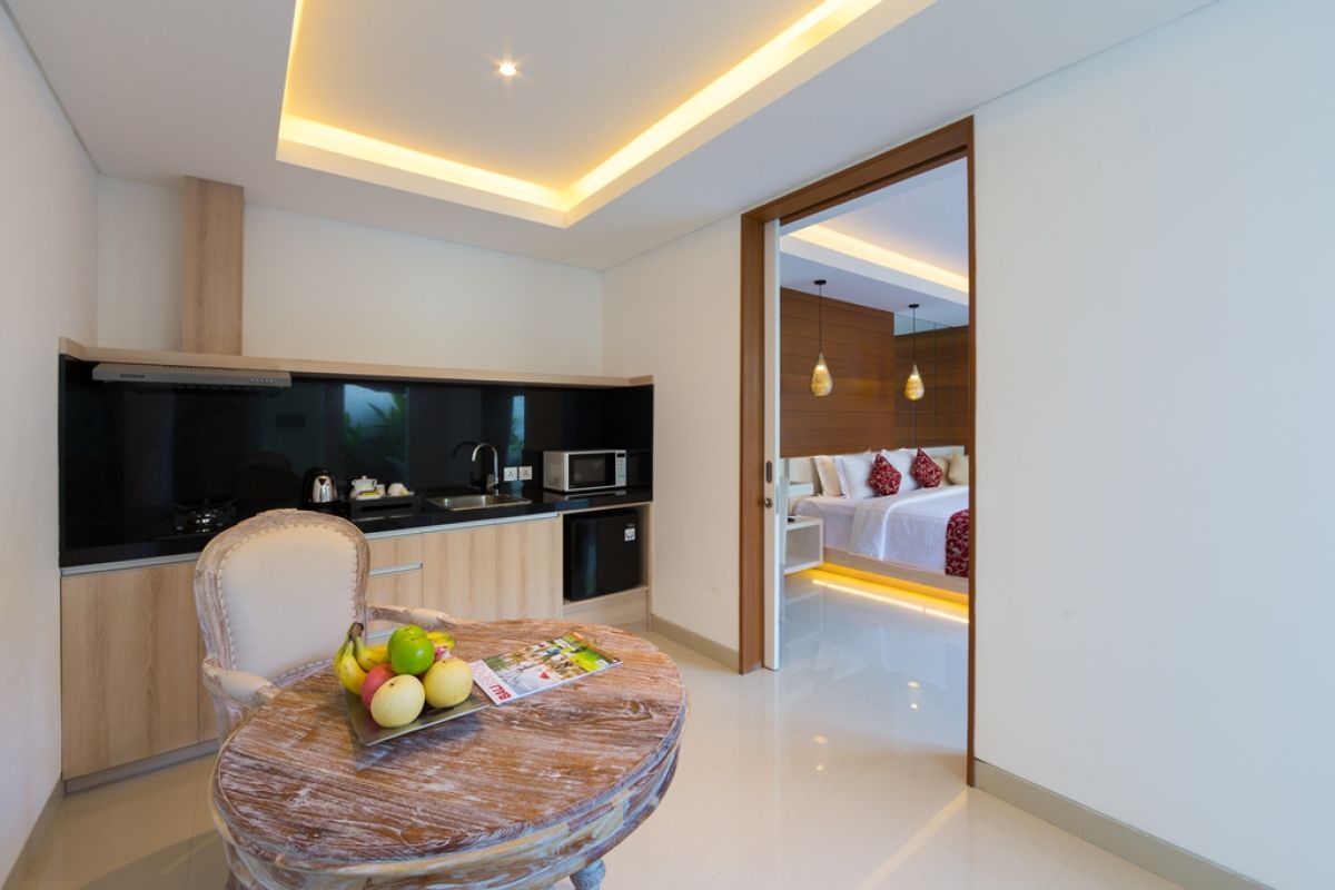 Spacious Balinese villa bedroom with wooden walls, white king bed, red accents, and sliding doors to a private infinity pool. - Bali Villas