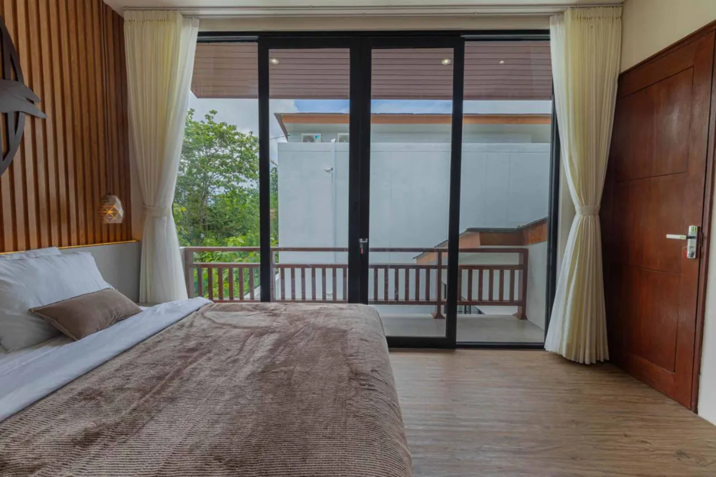 Modern minimalist kitchen with wooden cabinets, white orchids on a central table, fridge, and sink. - Bali Villas