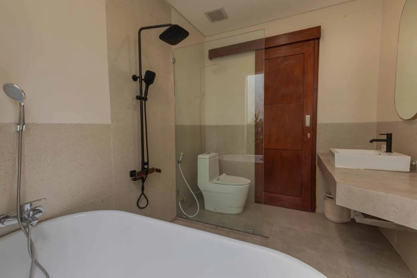 Modern minimalist kitchen with wooden cabinets, white orchids on a central table, fridge, and sink. - Bali Villas