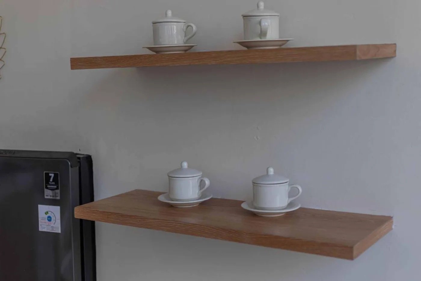 Modern minimalist kitchen with wooden cabinets, white orchids on a central table, fridge, and sink. - Bali Villas