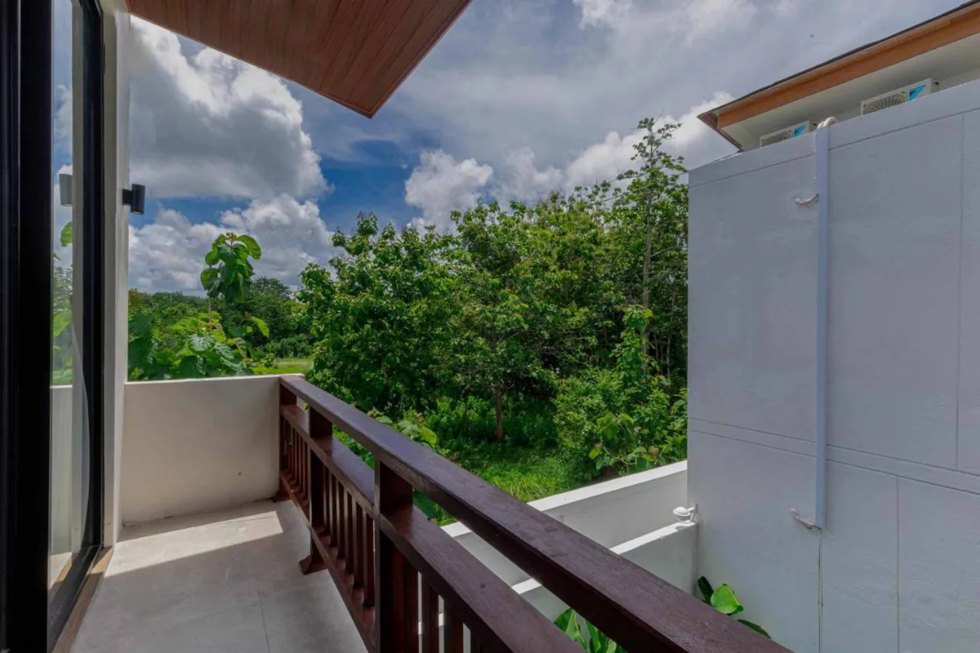 Modern minimalist kitchen with wooden cabinets, white orchids on a central table, fridge, and sink. - Bali Villas