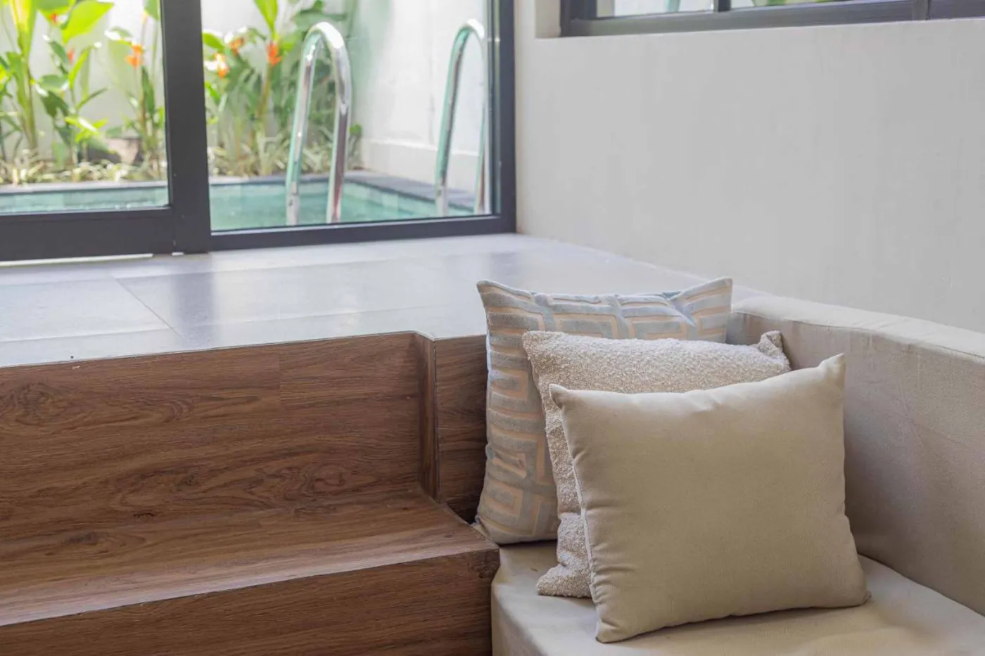 Modern minimalist kitchen with wooden cabinets, white orchids on a central table, fridge, and sink. - Bali Villas