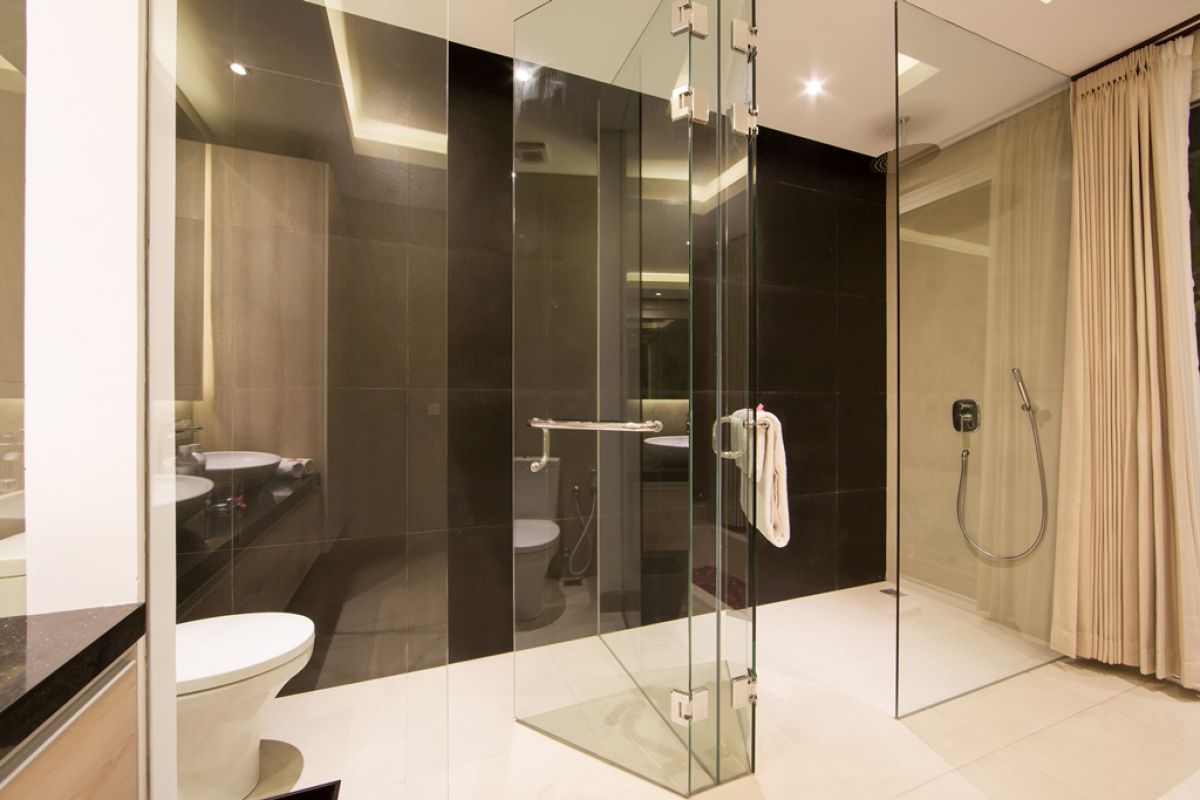 Luxurious Balinese villa terrace at night: wooden table with red petals, white armchairs, tropical banana plants, and sliding glass doors to bedroom. - Bali Villas