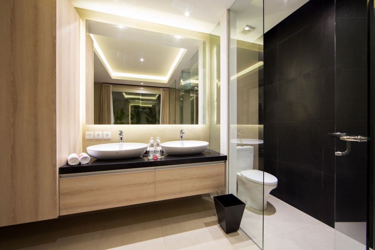 Luxurious Balinese villa terrace at night: wooden table with red petals, white armchairs, tropical banana plants, and sliding glass doors to bedroom. - Bali Villas