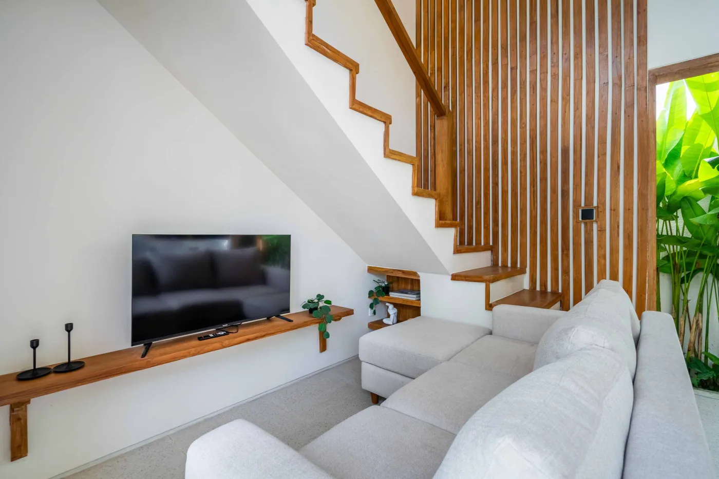 Modern minimalist bathroom with white freestanding bathtub, black rainfall showerhead, and sleek wall niche holding toiletries. - Bali Villas