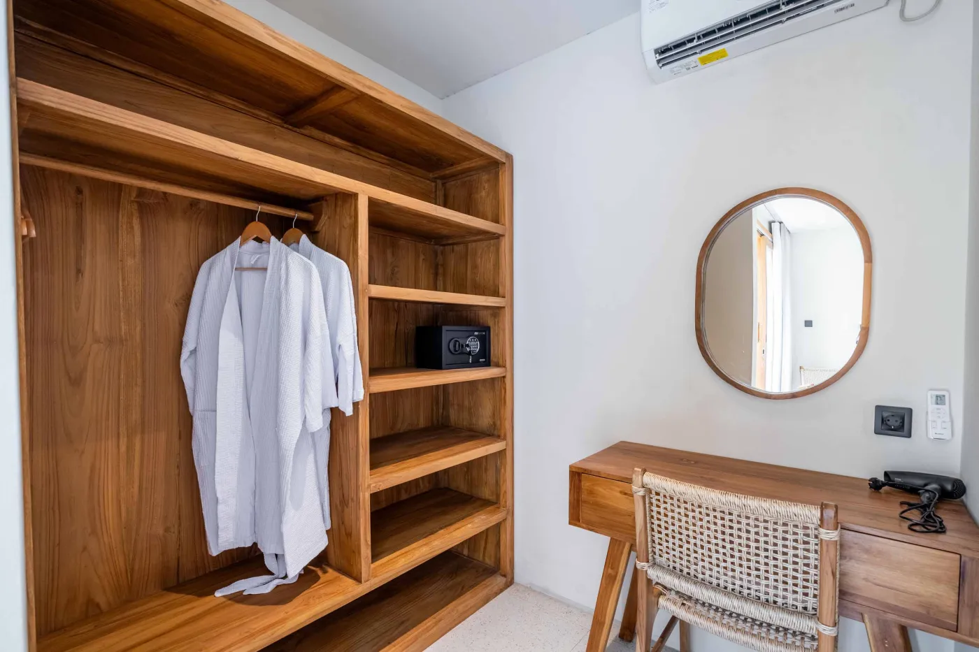 Modern minimalist bathroom with white freestanding bathtub, black rainfall showerhead, and sleek wall niche holding toiletries. - Bali Villas