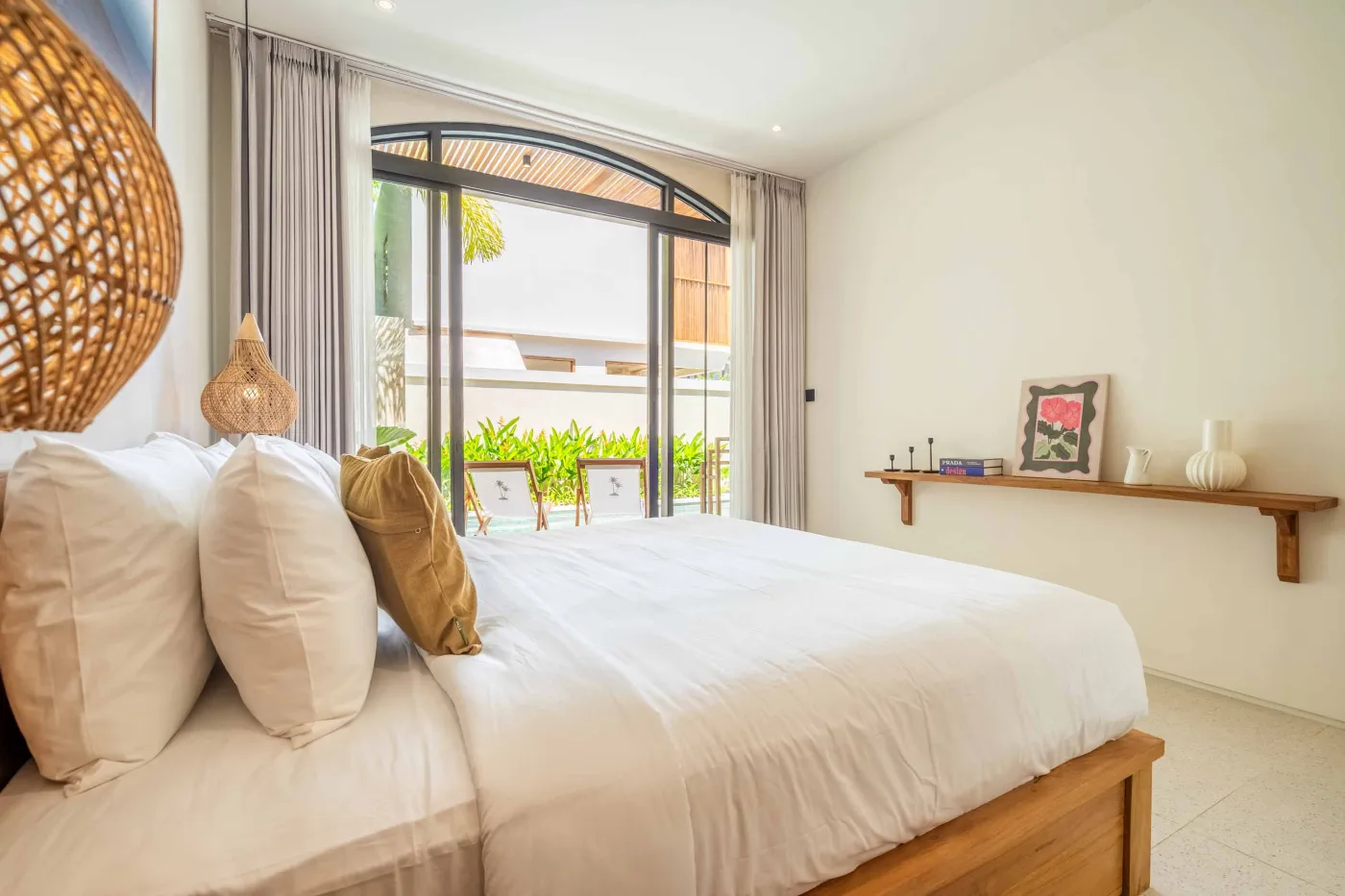 Luxurious tropical bathroom with white freestanding bathtub, rainfall shower, lush green plants, and textured stone walls. - Bali Villas