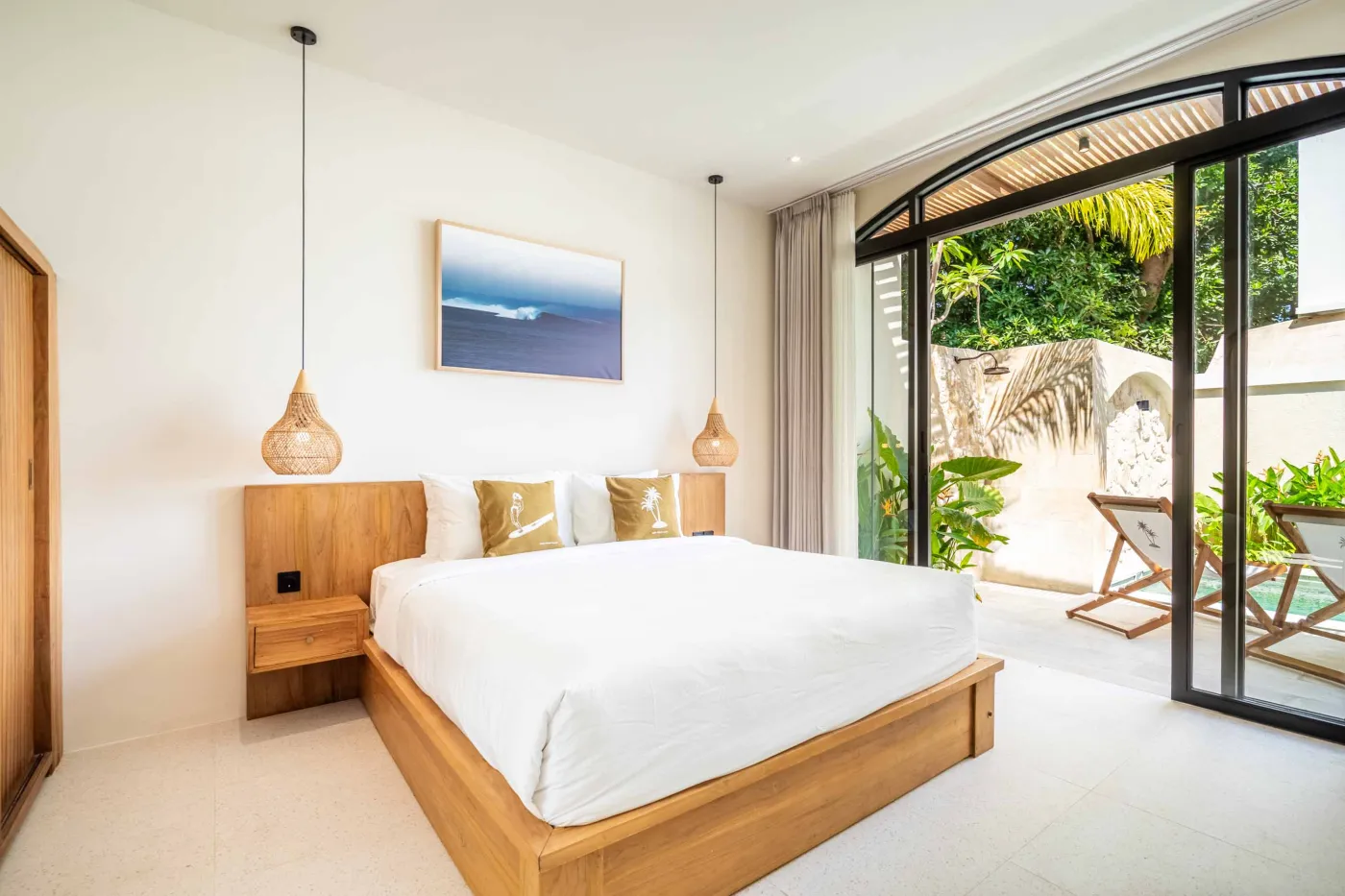 Luxurious tropical bathroom with white freestanding bathtub, rainfall shower, lush green plants, and textured stone walls. - Bali Villas
