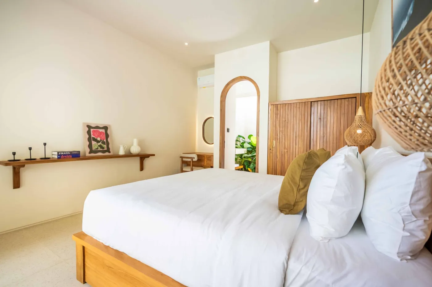 Luxurious tropical bathroom with white freestanding bathtub, rainfall shower, lush green plants, and textured stone walls. - Bali Villas