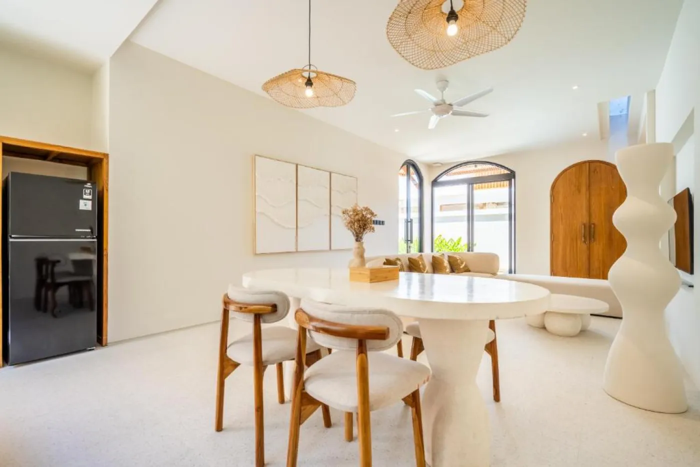 Luxurious tropical bathroom with white freestanding bathtub, rainfall shower, lush green plants, and textured stone walls. - Bali Villas