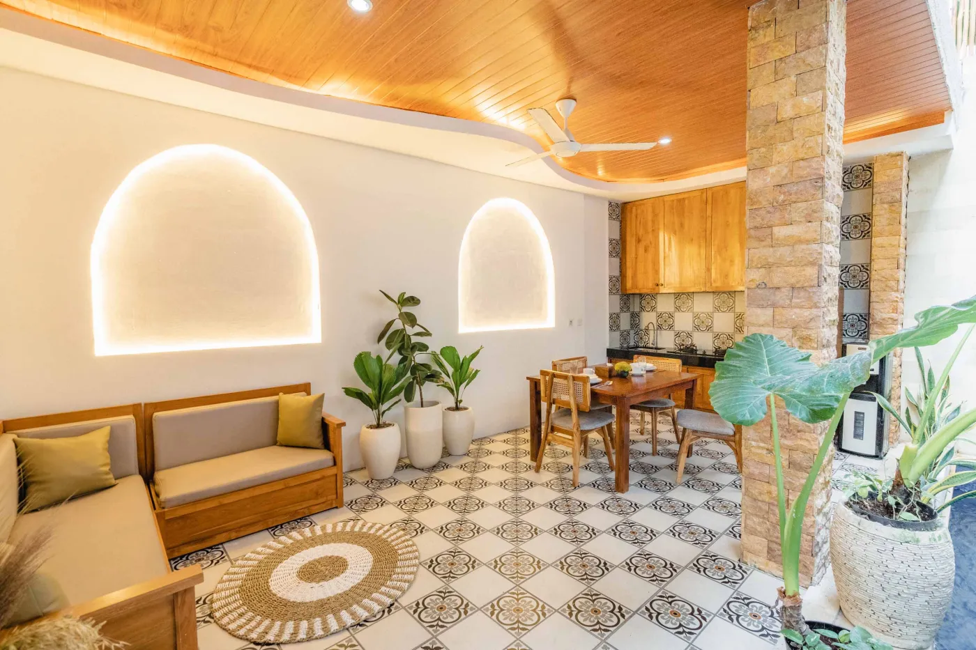 Balinese kitchen with wooden cabinets, checkered tiled backsplash, and dining table overlooking a private pool. - Bali Villas