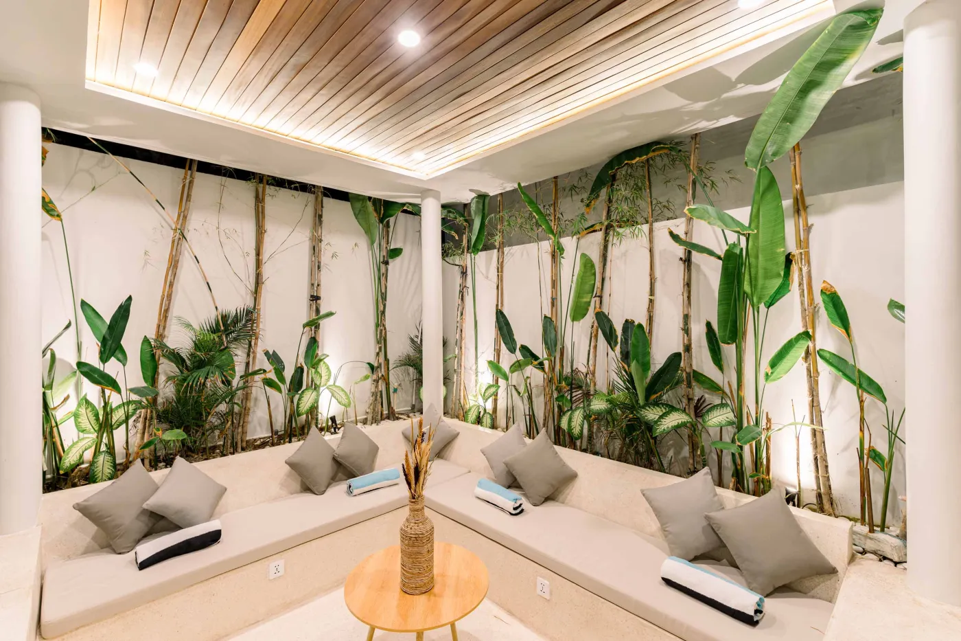 Luxurious modern bathroom featuring a white freestanding bathtub filled with water and red rose petals, adjacent glass shower, large window, and potted plant. - Bali Villas
