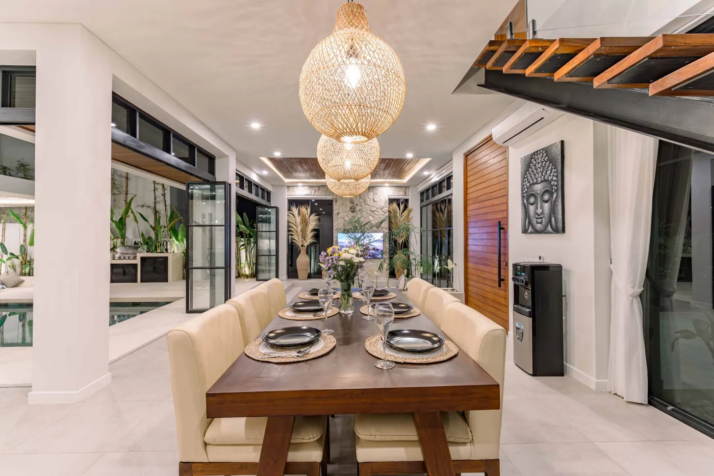 Luxurious modern bathroom featuring a white freestanding bathtub filled with water and red rose petals, adjacent glass shower, large window, and potted plant. - Bali Villas