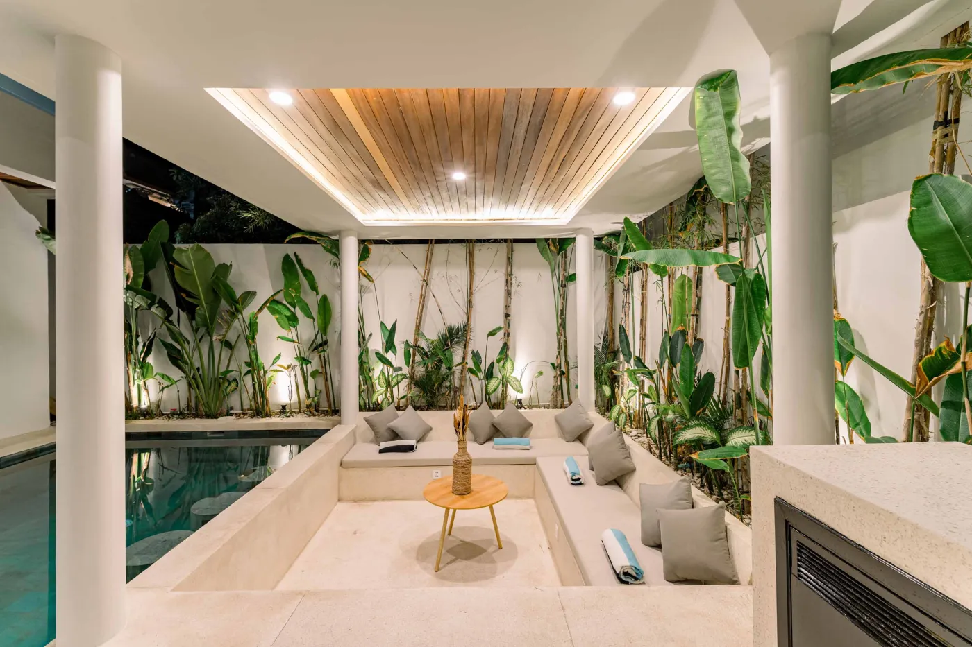 Luxurious modern bathroom featuring a white freestanding bathtub filled with water and red rose petals, adjacent glass shower, large window, and potted plant. - Bali Villas