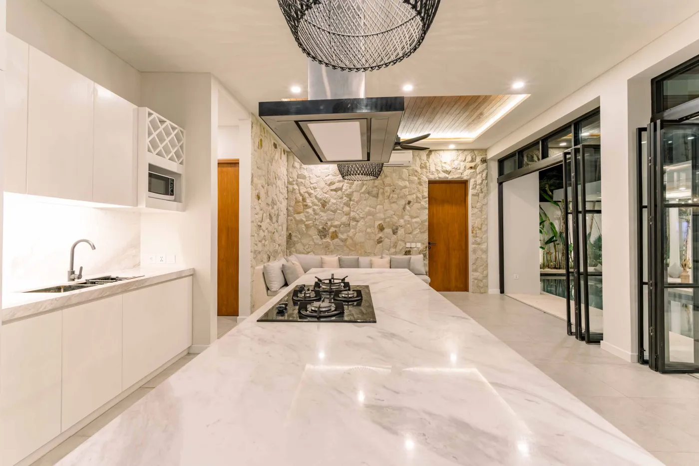 Luxurious modern bathroom featuring a white freestanding bathtub filled with water and red rose petals, adjacent glass shower, large window, and potted plant. - Bali Villas