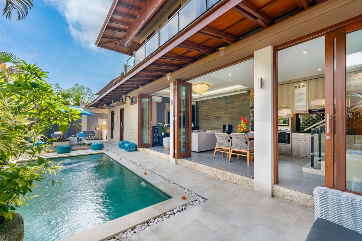 Spacious Balinese terrace pavilion with white rattan sofa, blue cushions, coffee table, and ocean horizon view. - Bali Villas