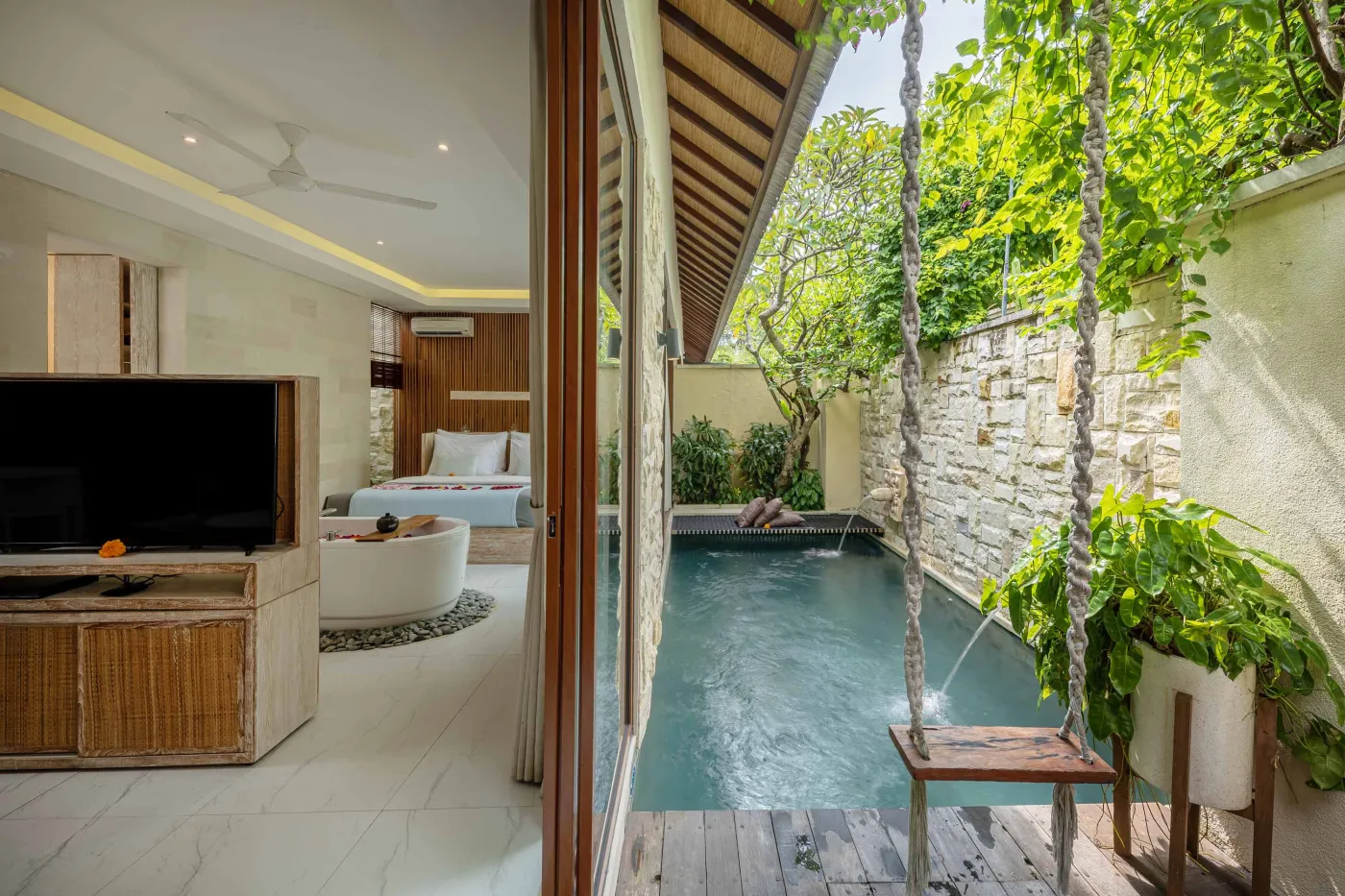 Luxury Bali villa bedroom with sliding doors opening to a private plunge pool and tropical garden swing. - Bali Villas