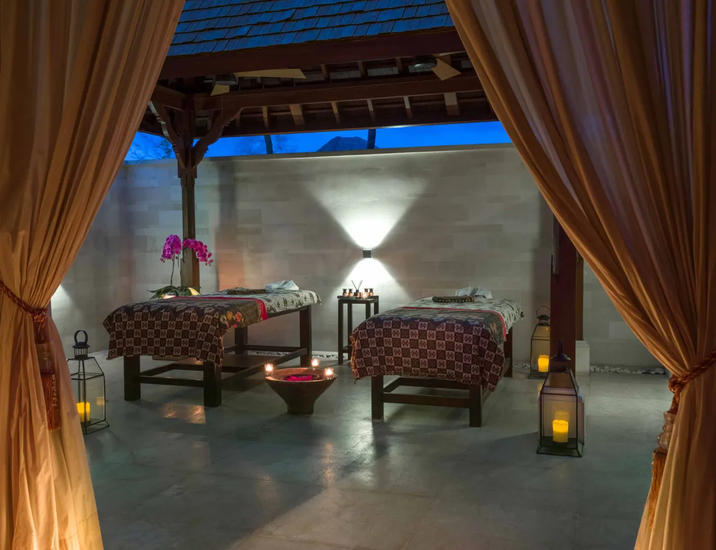 Curved stone terrace with white cushioned lounge overlooking Bali beach, ocean, and tropical gardens. - Bali Villas