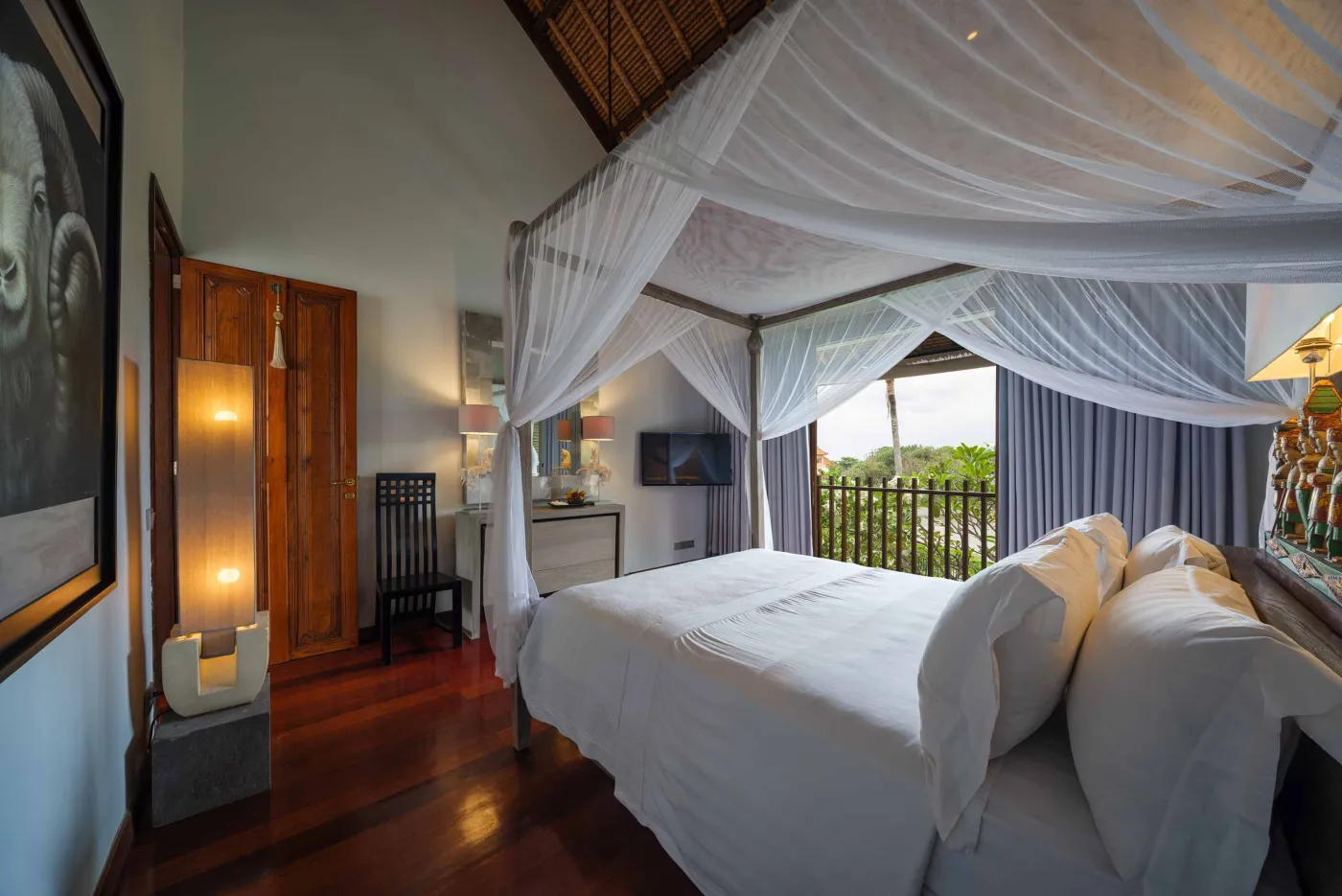 Curved stone terrace with white cushioned lounge overlooking Bali beach, ocean, and tropical gardens. - Bali Villas