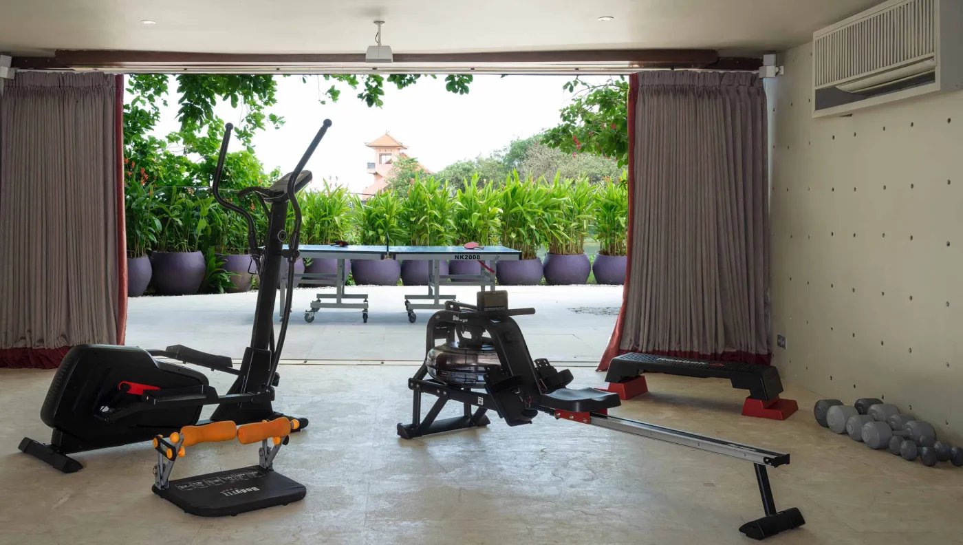 Curved stone terrace with white cushioned lounge overlooking Bali beach, ocean, and tropical gardens. - Bali Villas