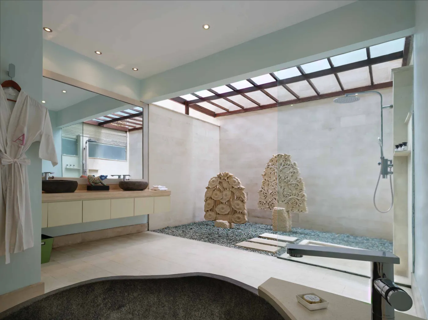 Curved stone terrace with white cushioned lounge overlooking Bali beach, ocean, and tropical gardens. - Bali Villas