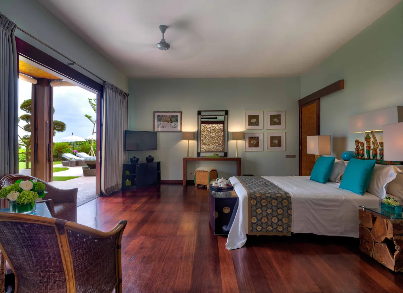 Curved stone terrace with white cushioned lounge overlooking Bali beach, ocean, and tropical gardens. - Bali Villas