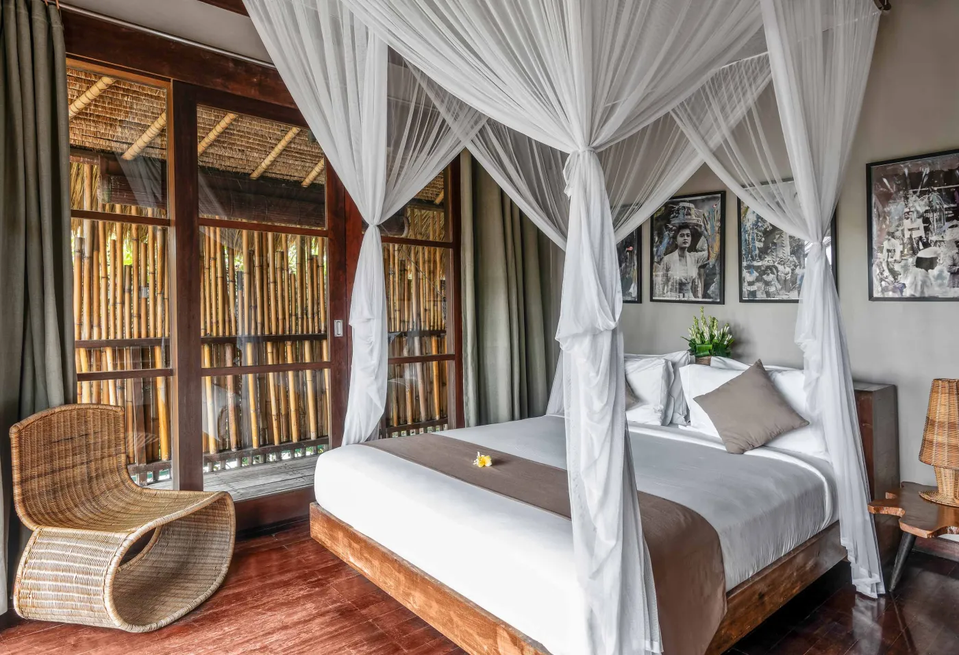 Spacious Balinese pavilion interior with thatched roof, white modular sofas, woven accents, and lush garden view through open wooden frames. - Bali Villas