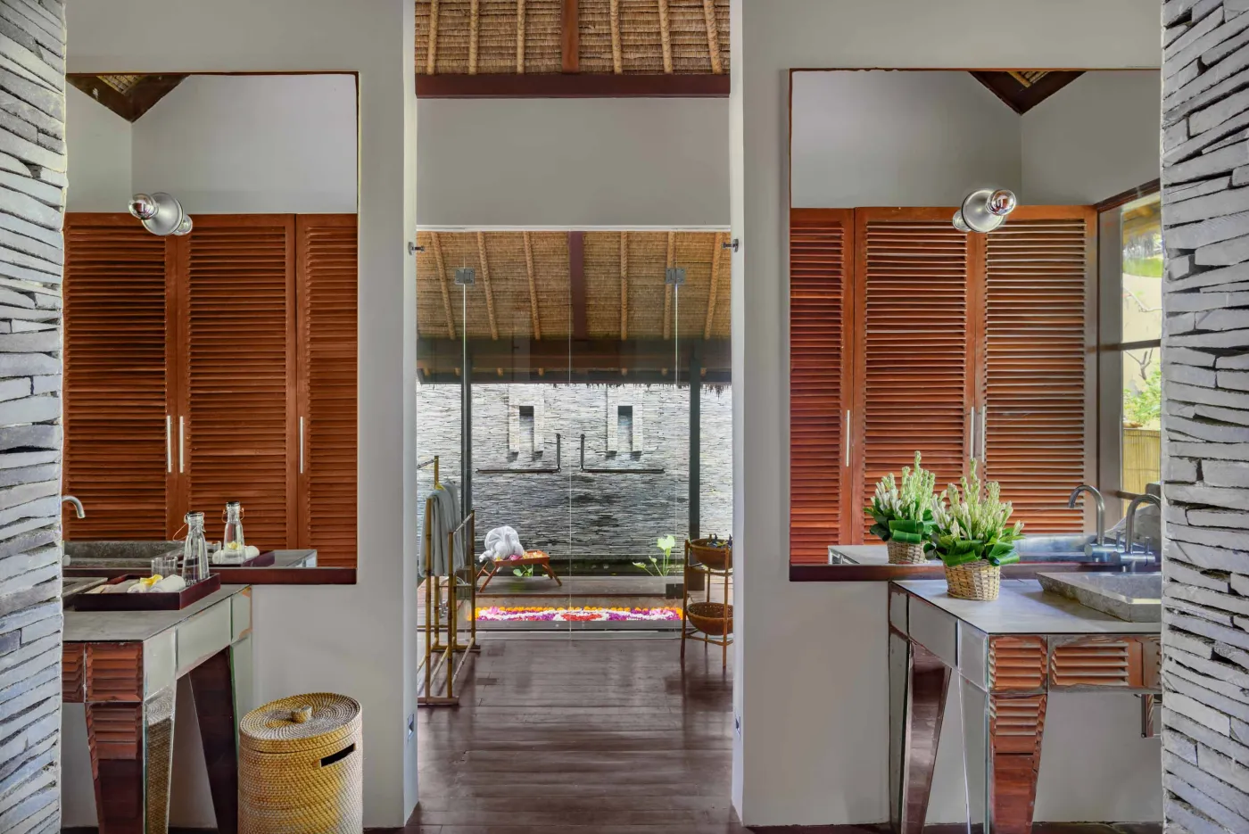 Spacious Balinese pavilion interior with thatched roof, white modular sofas, woven accents, and lush garden view through open wooden frames. - Bali Villas