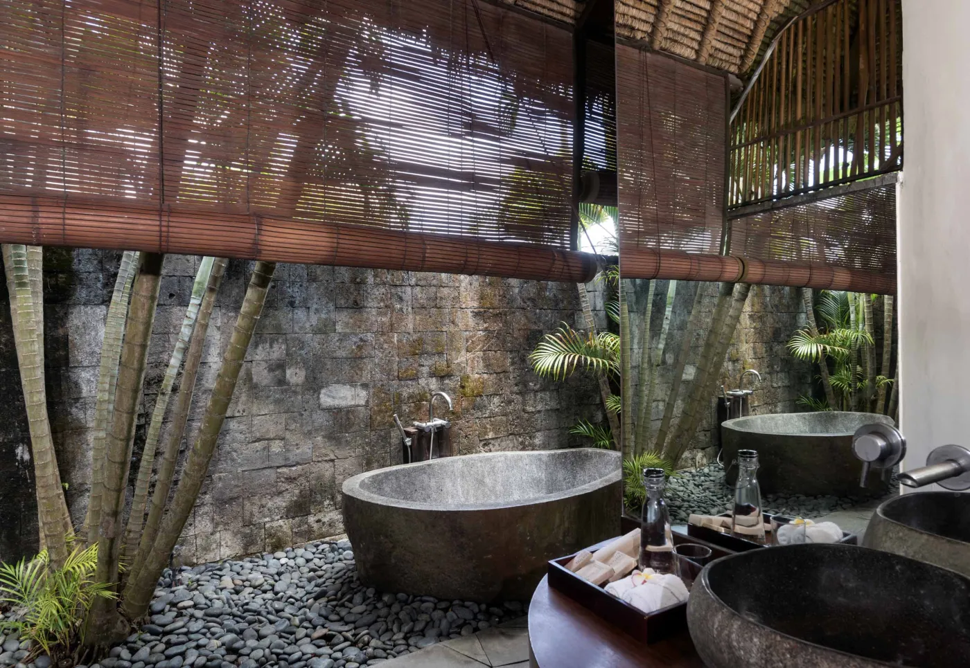 Spacious Balinese pavilion interior with thatched roof, white modular sofas, woven accents, and lush garden view through open wooden frames. - Bali Villas