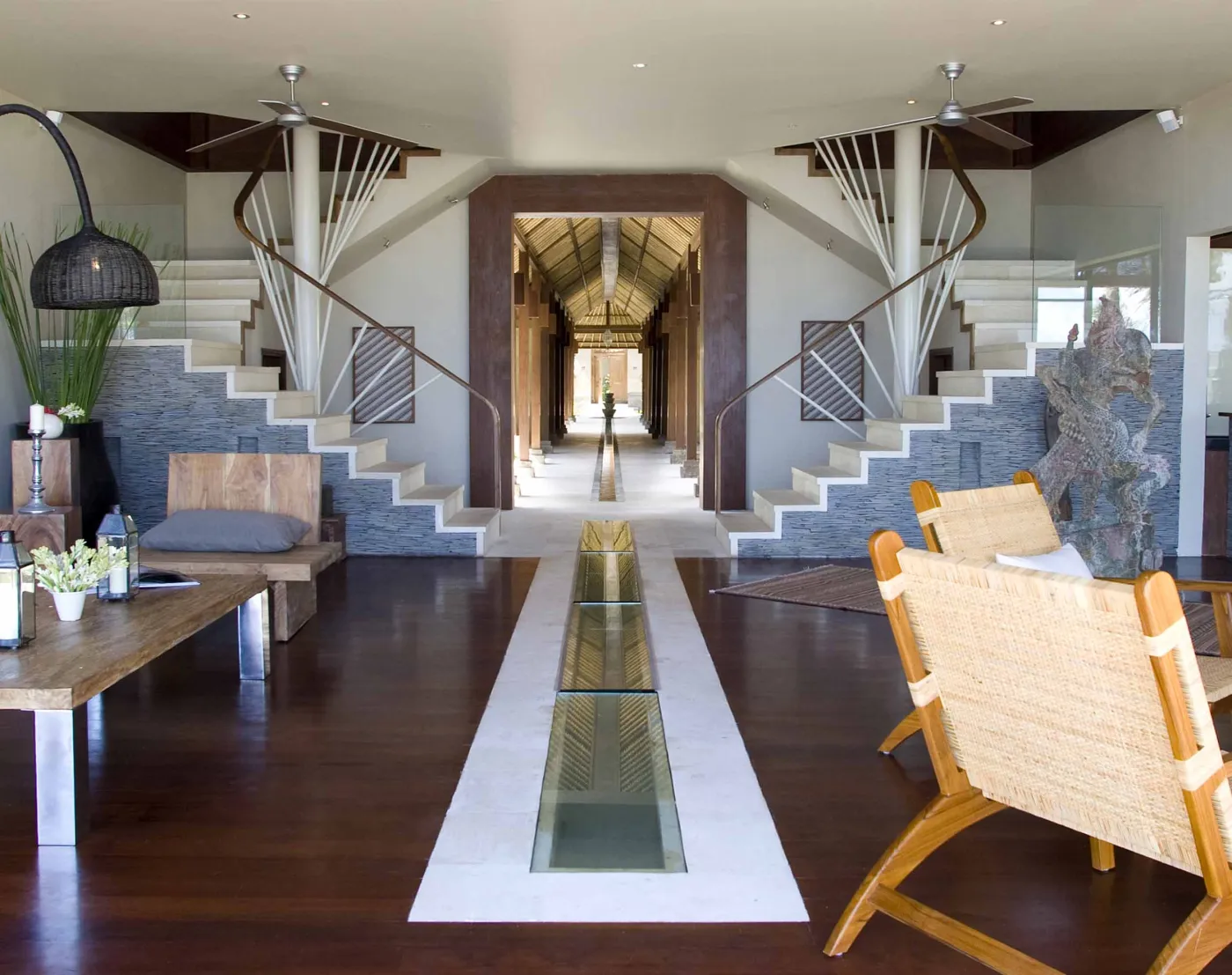 Luxury infinity pool at Bali beach resort, with loungers, umbrellas, tropical trees, and ocean view. - Bali Villas