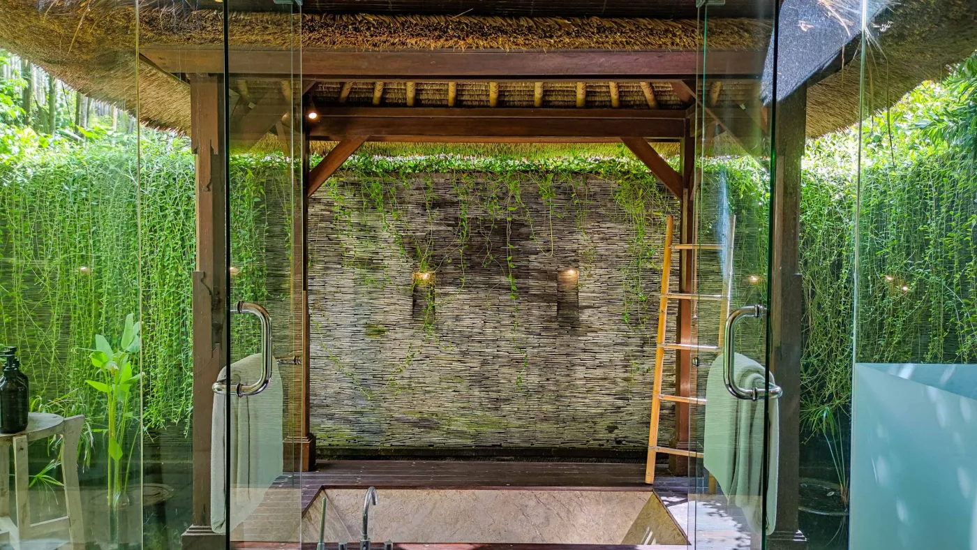 Luxury infinity pool at Bali beach resort, with loungers, umbrellas, tropical trees, and ocean view. - Bali Villas