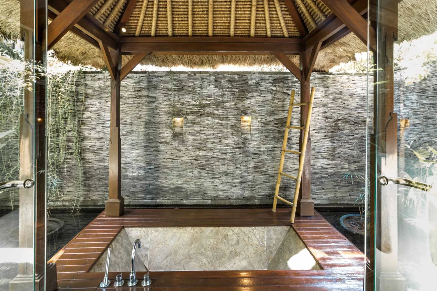 Luxury infinity pool at Bali beach resort, with loungers, umbrellas, tropical trees, and ocean view. - Bali Villas