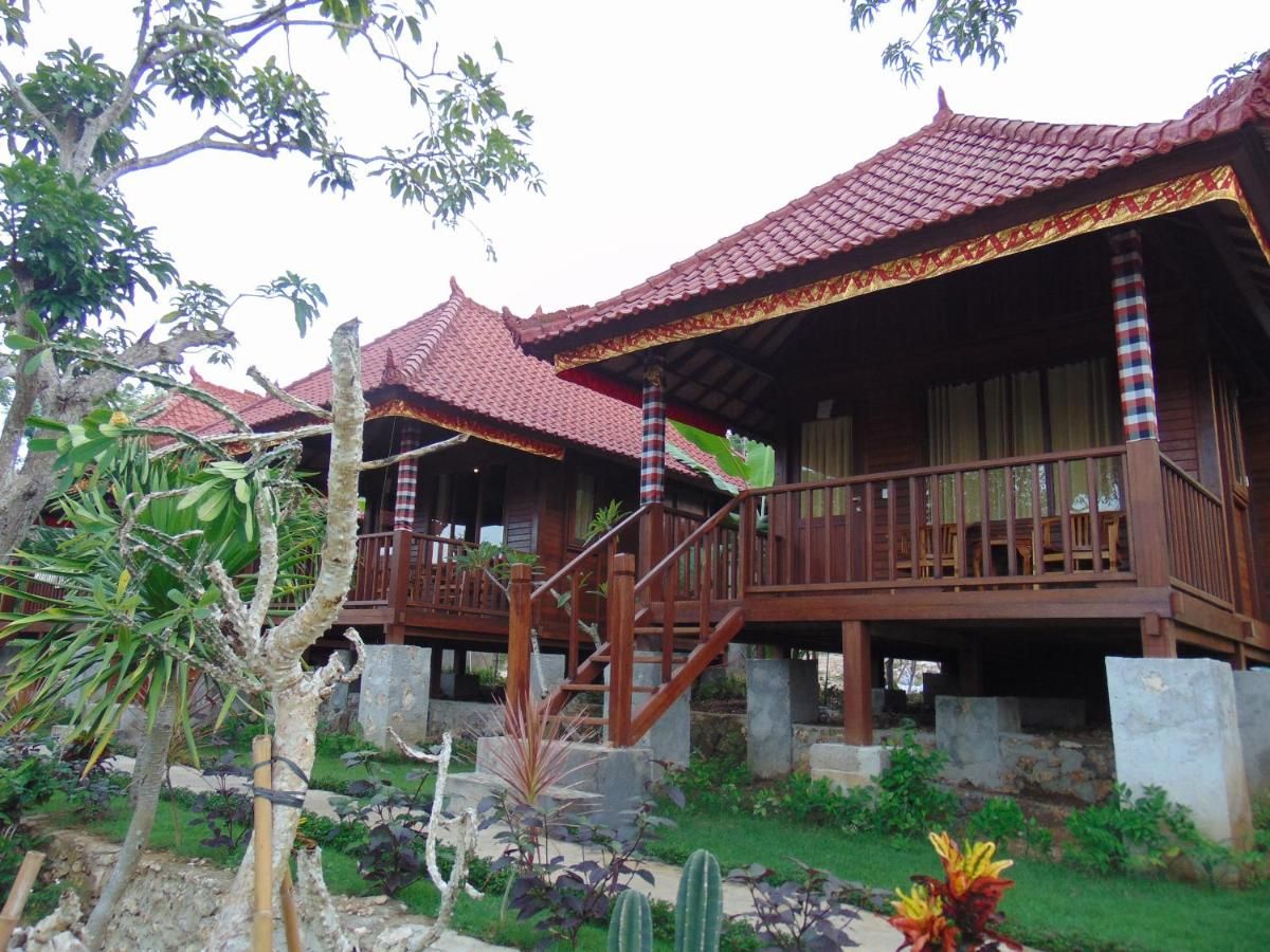 Rustic tropical bathroom with wooden walls, pebble tile floor, woven sink basin, and open shower. - Bali Villas