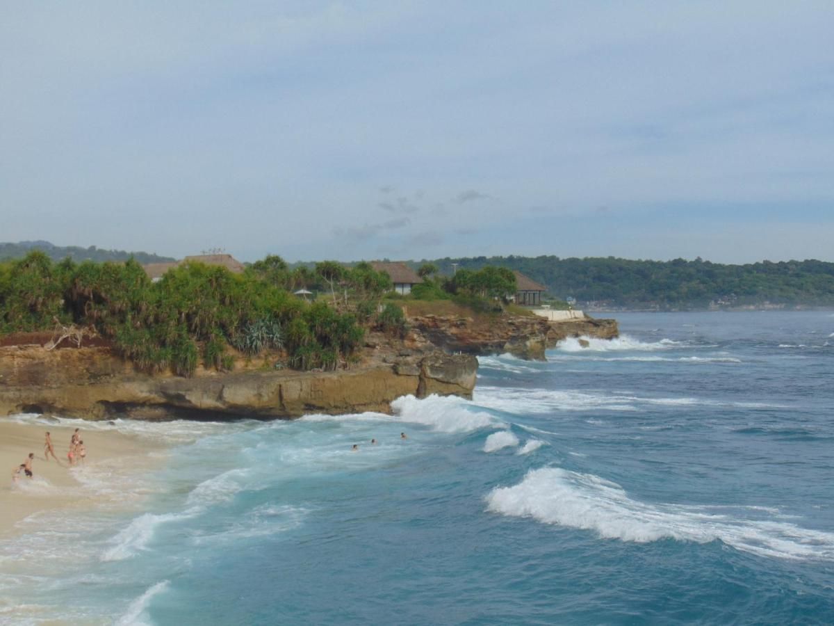 Rustic tropical bathroom with wooden walls, pebble tile floor, woven sink basin, and open shower. - Bali Villas