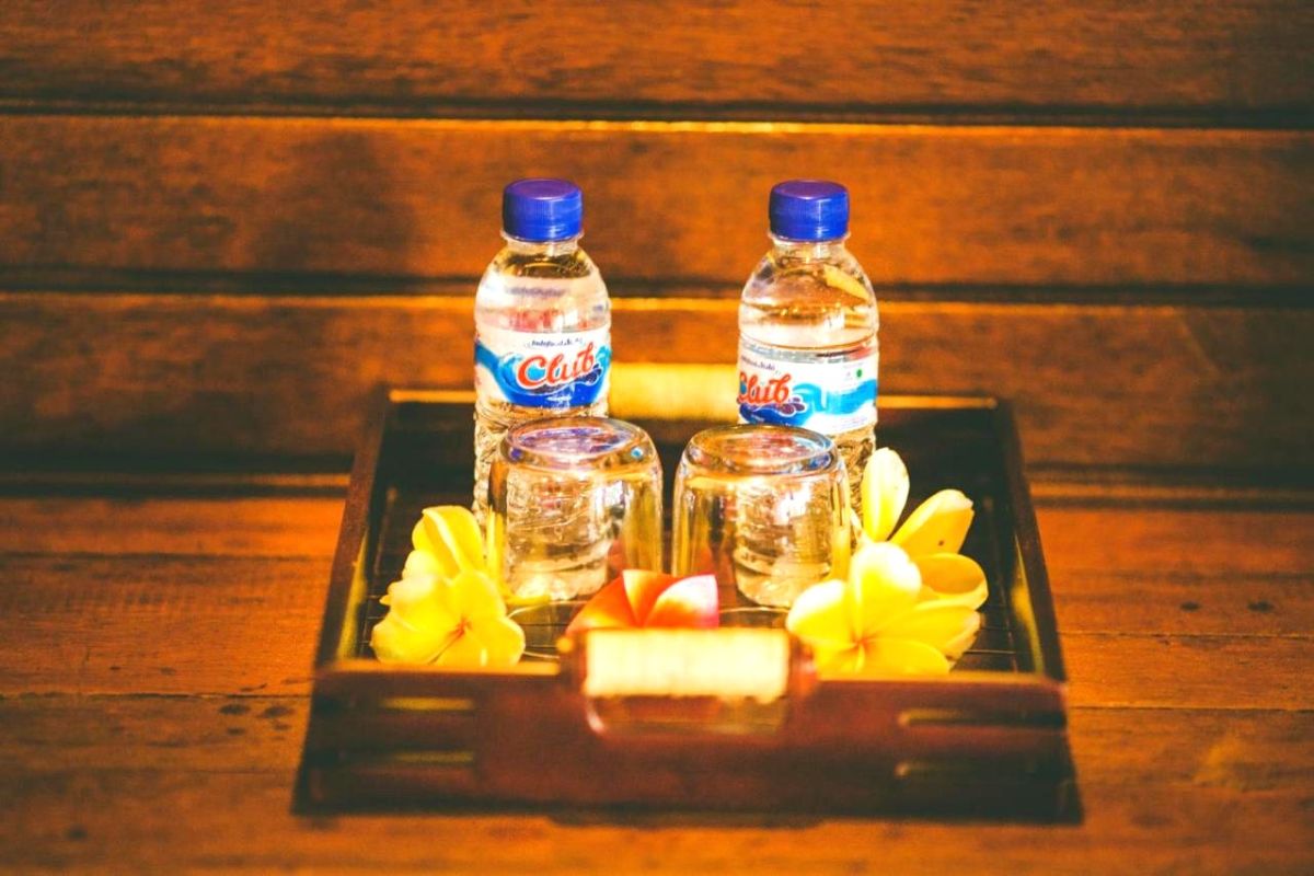 Rustic tropical bathroom with wooden walls, pebble tile floor, woven sink basin, and open shower. - Bali Villas