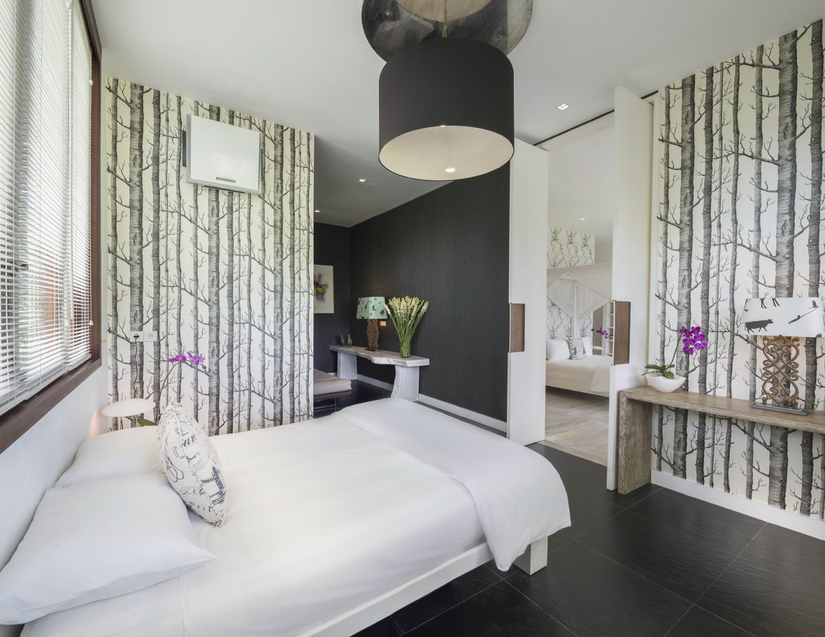 Luxurious spa bathroom with a freestanding tub filled with red rose petals and floating candles, orchids, white towels, and bamboo-shaded tropical window. - Bali Villas
