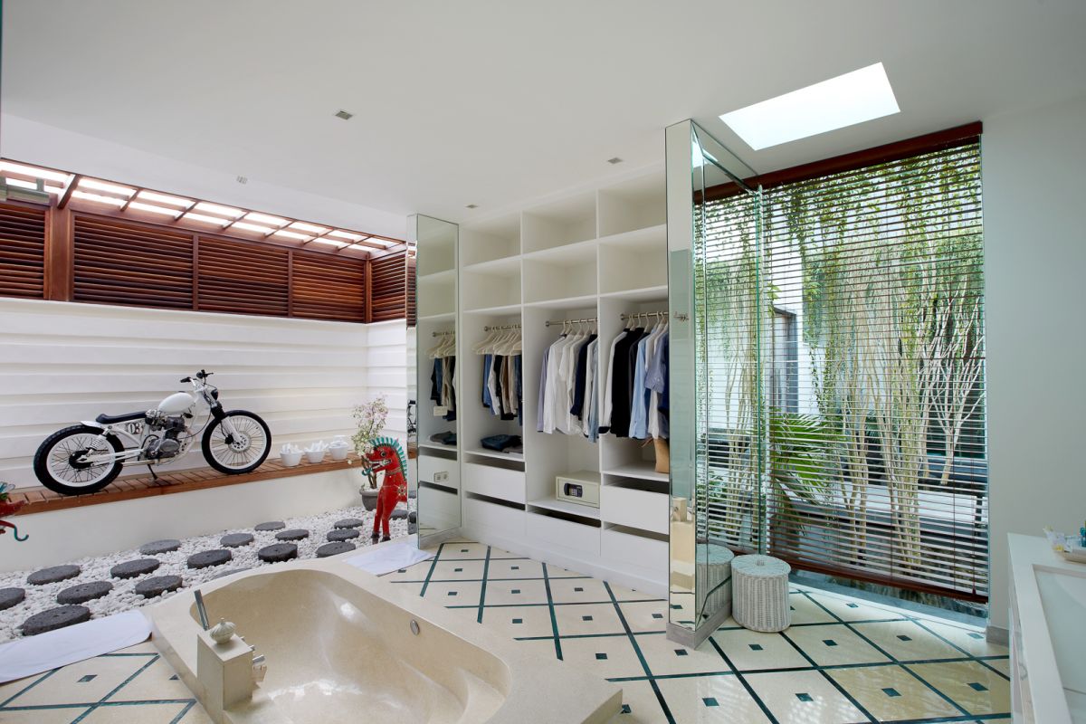 Luxurious spa bathroom with a freestanding tub filled with red rose petals and floating candles, orchids, white towels, and bamboo-shaded tropical window. - Bali Villas