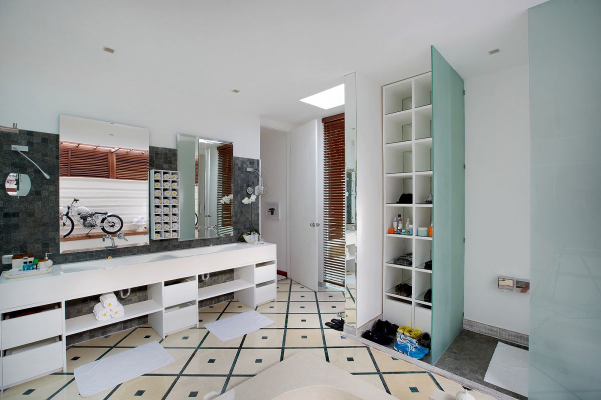 Luxurious spa bathroom with a freestanding tub filled with red rose petals and floating candles, orchids, white towels, and bamboo-shaded tropical window. - Bali Villas