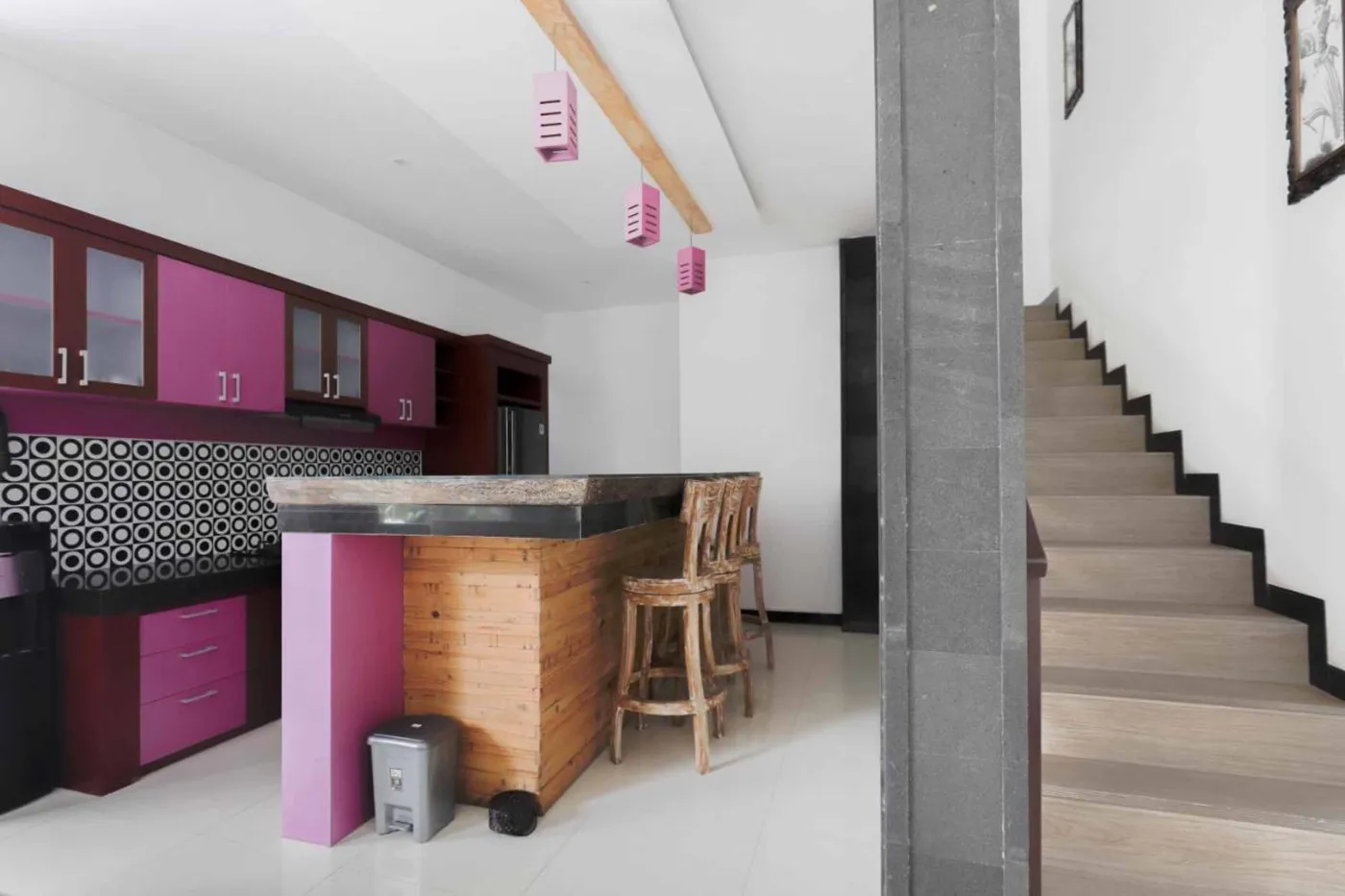Modern bathroom with wooden bowl sink on black vanity, white toilet, glass shower enclosure, and neutral tiled walls. - Bali Villas