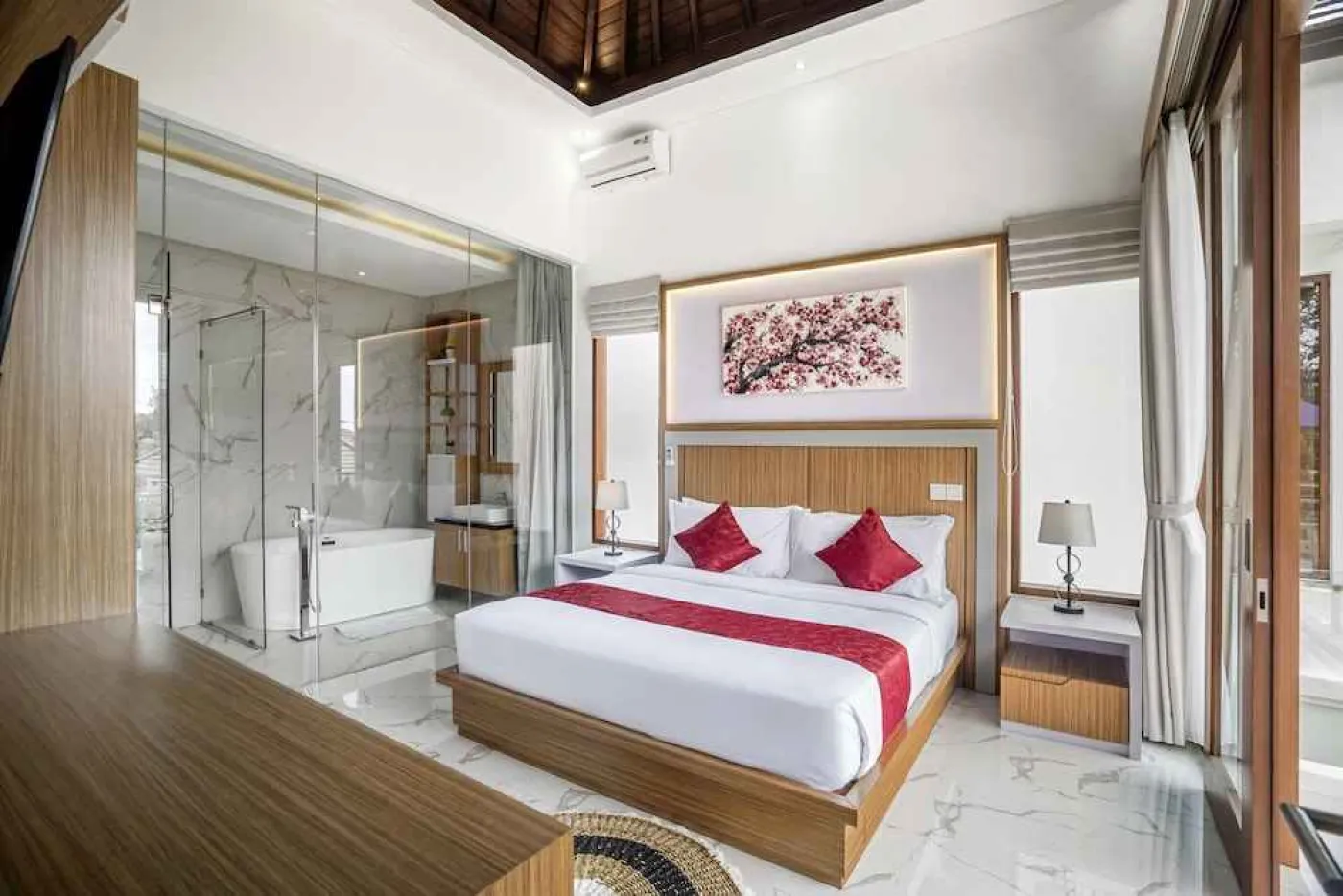 Serene tropical poolside at a modern Balinese villa, with lounge chairs under an orange umbrella, lush greenery, and open indoor living area at dusk. - Bali Villas