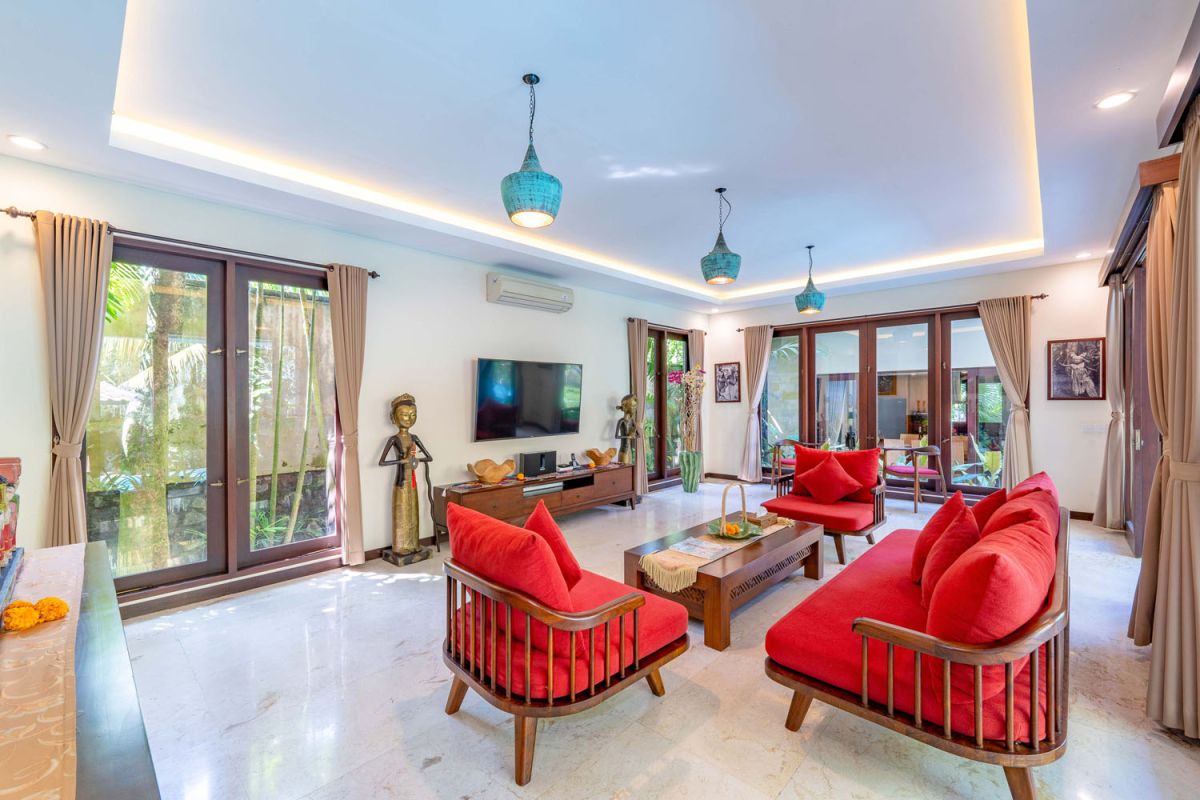 Modern tropical kitchen interior with black granite countertop, wooden cabinets, fresh pineapple and dragon fruit bowl, potted plants, and lush palm view through window. - Bali Villas