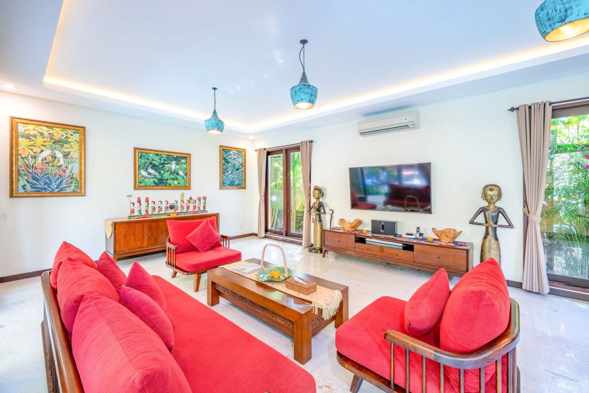 Modern tropical kitchen interior with black granite countertop, wooden cabinets, fresh pineapple and dragon fruit bowl, potted plants, and lush palm view through window. - Bali Villas