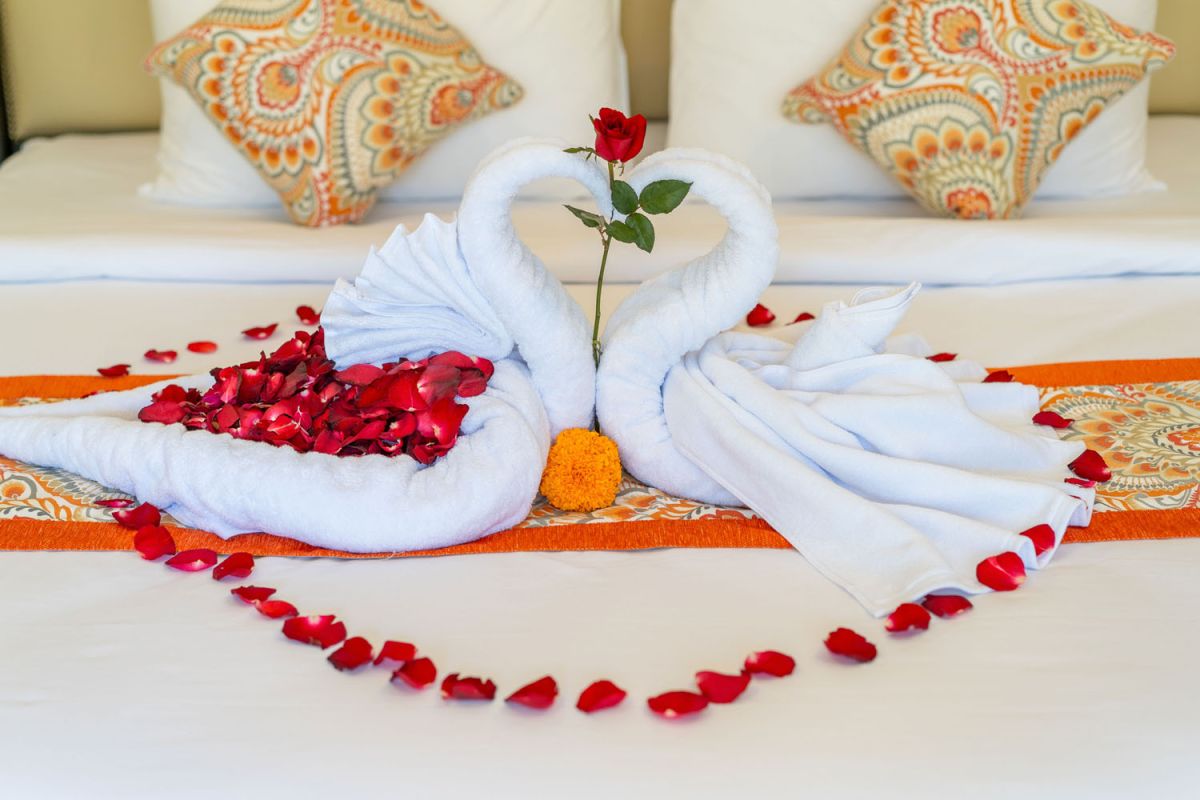 Modern tropical kitchen interior with black granite countertop, wooden cabinets, fresh pineapple and dragon fruit bowl, potted plants, and lush palm view through window. - Bali Villas