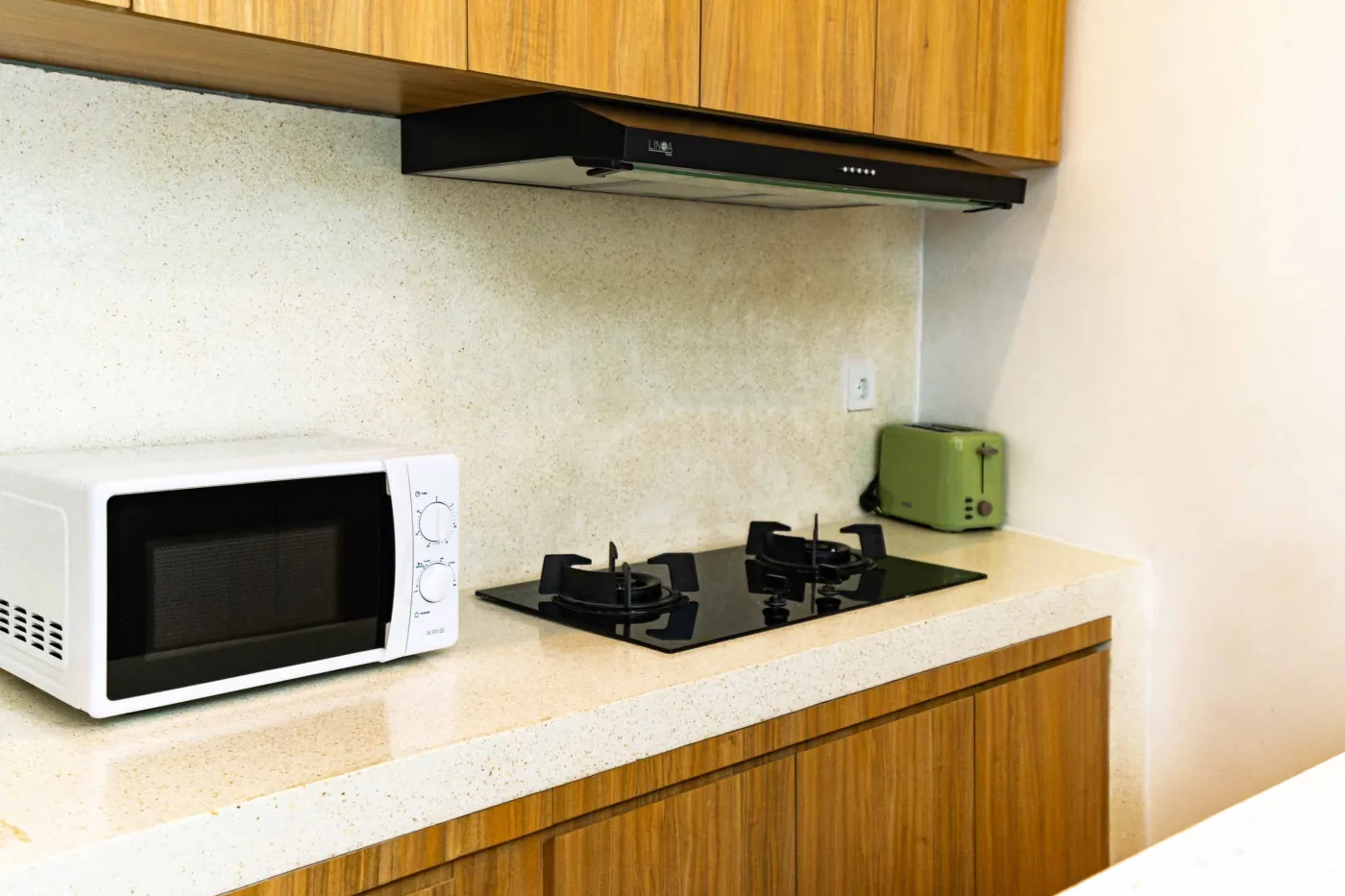 Luxurious modern bathroom with textured stone walls, arched black-framed windows overlooking tropical palms, freestanding white bathtub filled with red petals, and sleek vanity sink. - Bali Villas