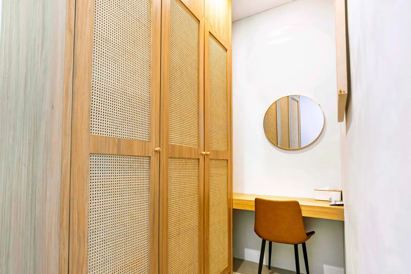 Luxurious modern bathroom with textured stone walls, arched black-framed windows overlooking tropical palms, freestanding white bathtub filled with red petals, and sleek vanity sink. - Bali Villas