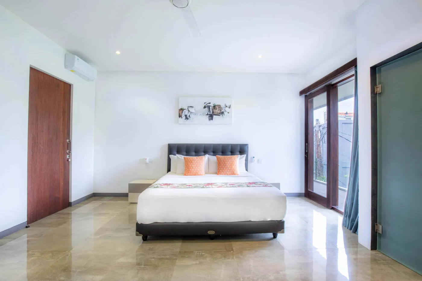 Modern black-tiled bathroom with freestanding white bathtub, handheld shower, and folded towels on rack. - Bali Villas