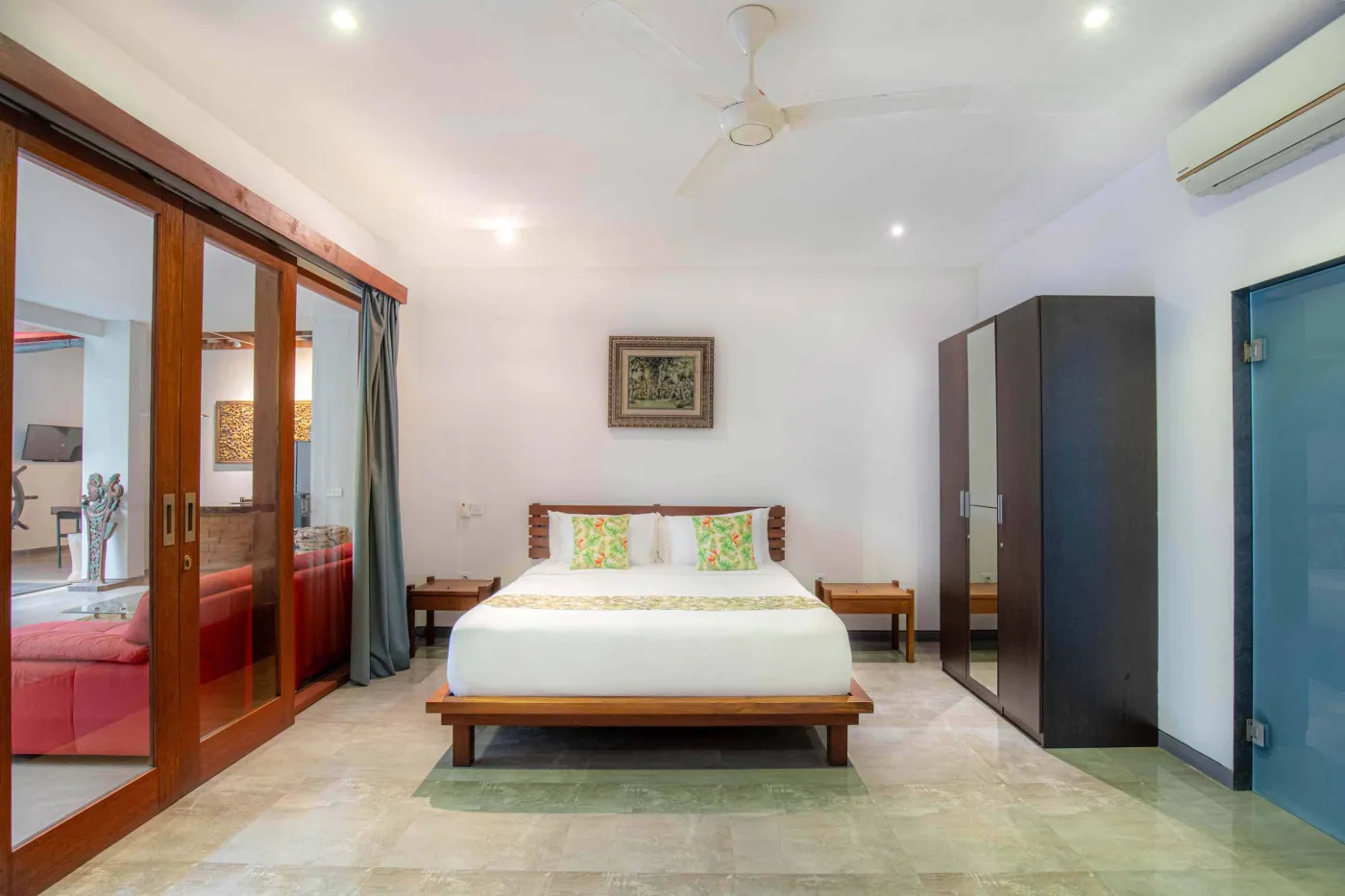 Modern black-tiled bathroom with freestanding white bathtub, handheld shower, and folded towels on rack. - Bali Villas