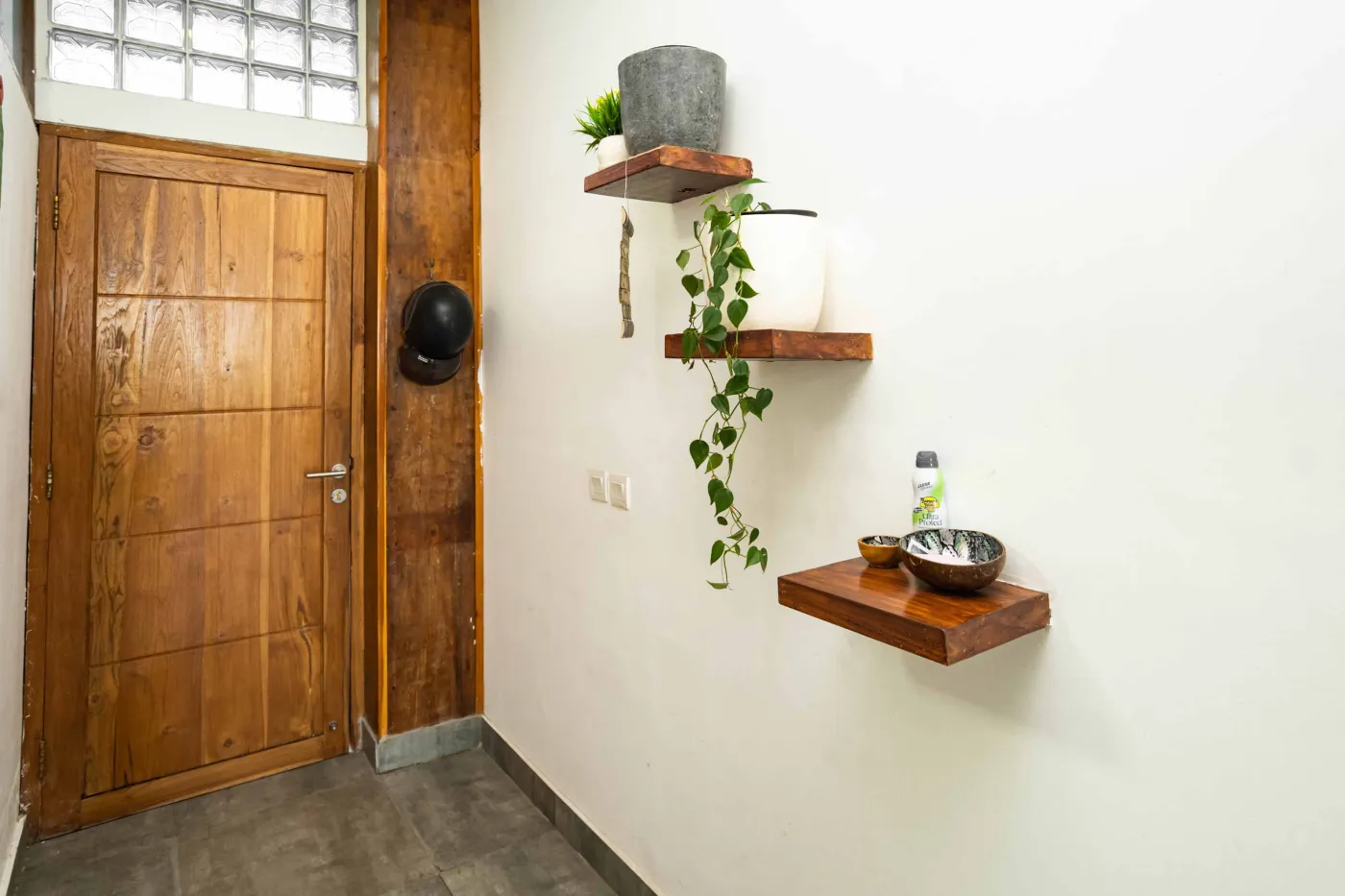 Cozy modern living room with green velvet sofa, wooden coffee table, potted plant, and adjacent white kitchen. - Bali Villas