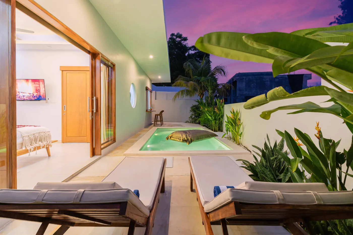 Modern minimalist interior with wooden desk, potted cactus in round window, rattan lamp, and tiled flooring. - Bali Villas